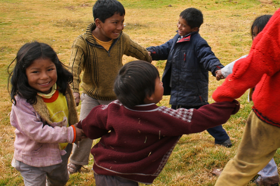 Niñas y niños jugando en rueda en un césped