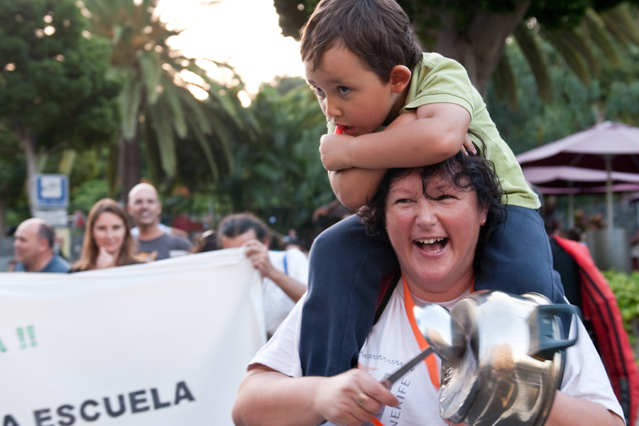 Mujer llevando a un niño pequeño en sus hombros, mientras golpea una cacería