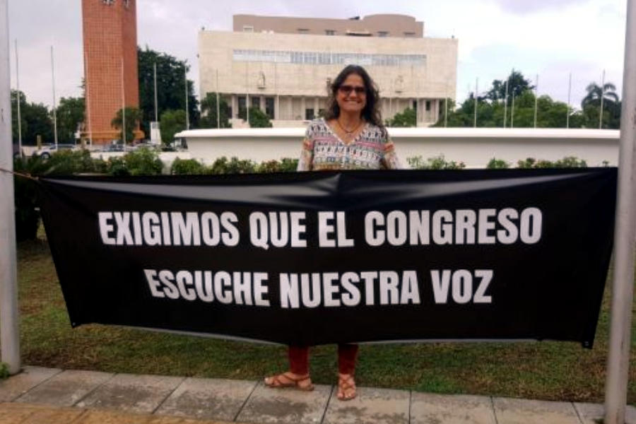 Mujer frente al Congreso dominicano con cartel en el que se lee 
