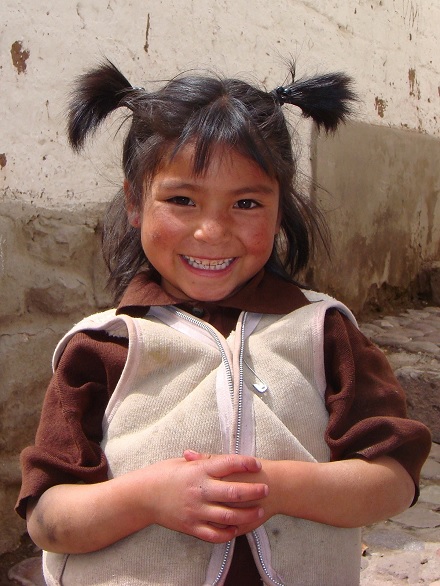 Niña peruana sonríe para la cámara. Ella está con uniforme escolar. 