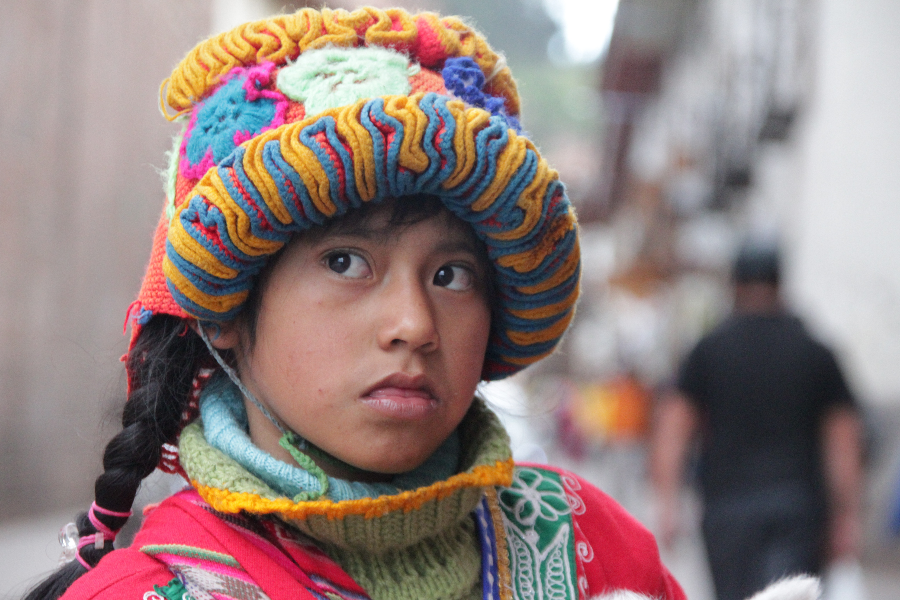 Foto del rostro de una adolescente peruana, mirando a un lado, con un gran sombrero tradicional