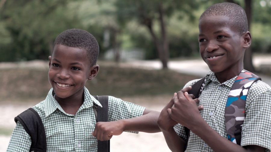 La privatización de la educación en África subsahariana aporta: familias más pobres tienden a frecuentar escuelas privadas de bajo costo y más. Imagen trae dos niños con mochilas que se parecen estar indo estudiar